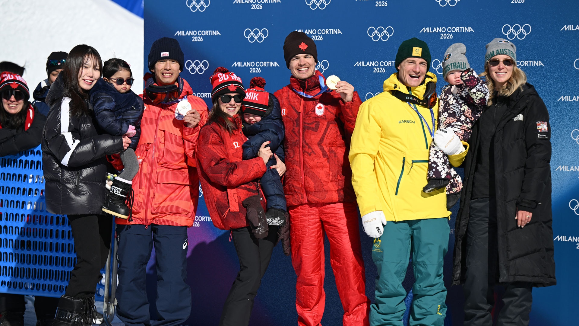 Mikael Kingsbury, Ikuma Horishima, and Matt Graham celebrate with their family members during the medal ceremony for the men's dual moguls final on day nine of the 2026 Winter Olympic Games in Livigno, Italy. 