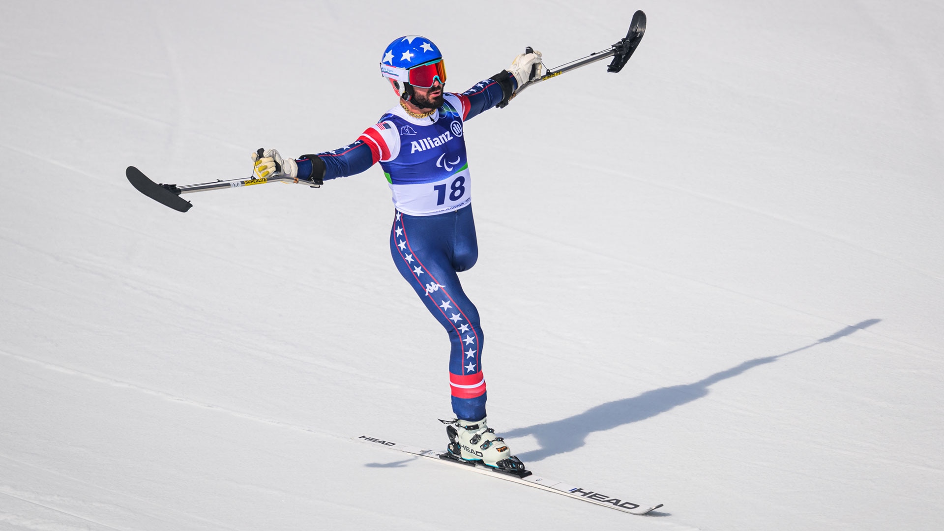 Patrick Halgren lifts his skis in celebration after finishing his run in the men's standing super-G at the Milan Cortina Paralympics