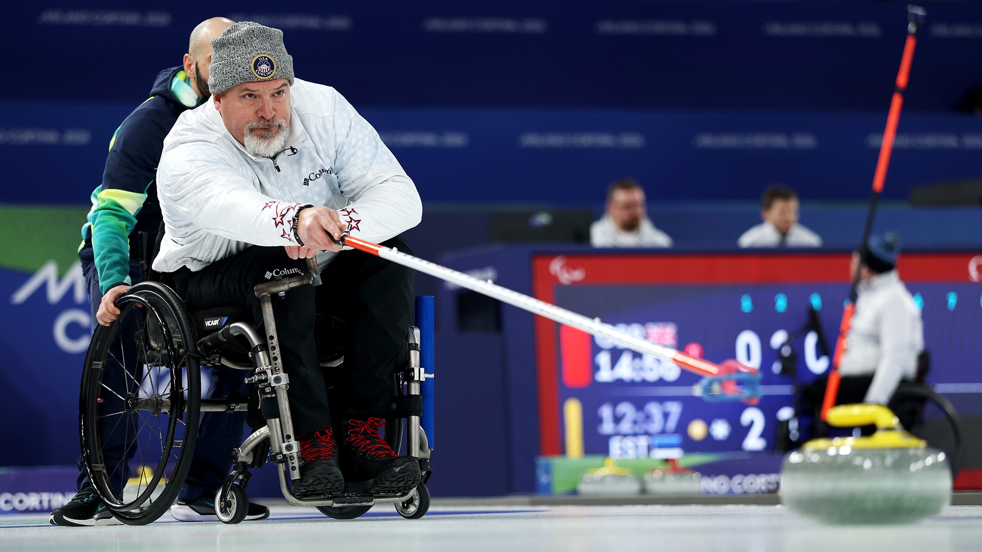 Wheelchair curler Steve Emt (USA) delivers a stone during round-robin mixed doubles play against Latvia at the 2026 Milan Cortina Paralympics.