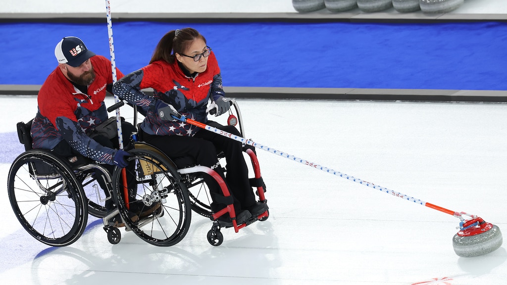 American Dan Rose helps teammate Oyuna Uranchimeg deliver a stone during the United States' round-robin mixed team matchup against Great Britain in Cortina.